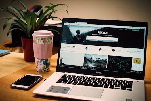 A tidy desk setting with a laptop showing a stock photo website and a smartphone.